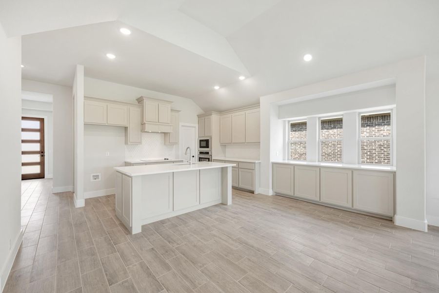 Open kitchen with gray cabinets, center island, stainless steel appliances, and wood-look tile floors