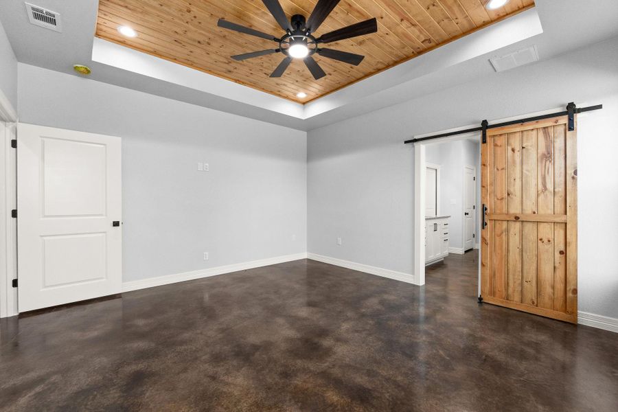 Spare room featuring a raised ceiling, a barn door, wood ceiling, concrete floors, and recessed lighting
