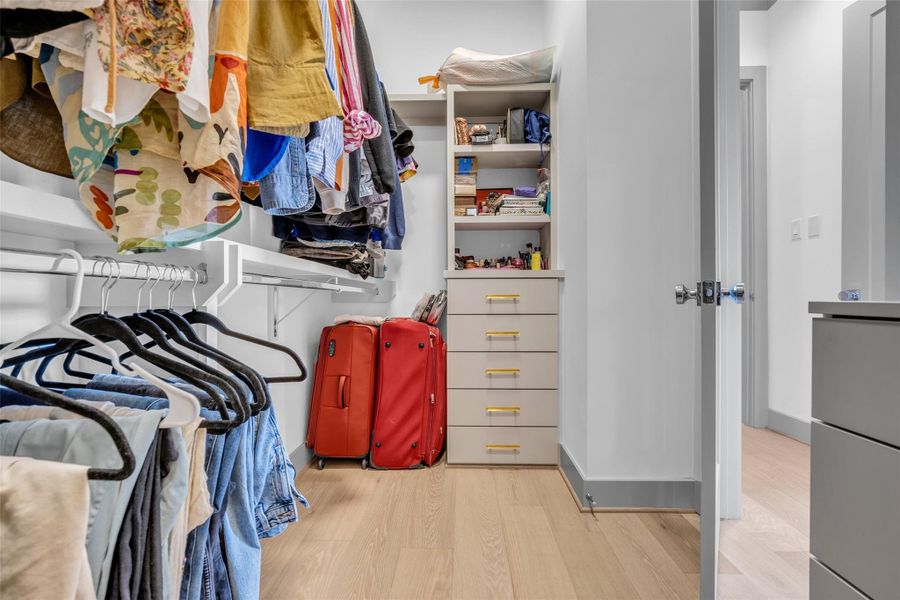 Primary bedroom includes a second walk-in closet located beside the primary bathroom, featuring built-in shelves and hanging racks for added storage and organization.