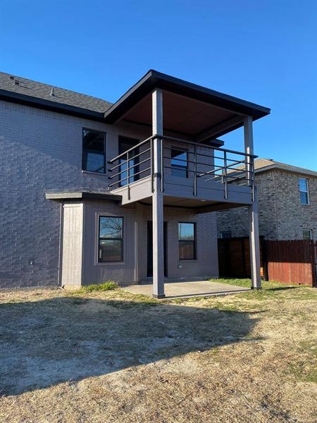 Rear view of property featuring a patio, a balcony, and a lawn