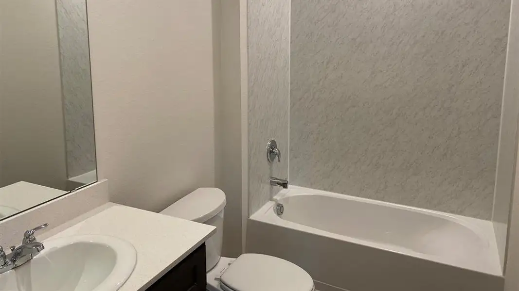 Full bathroom featuring vanity, bathtub / shower combination, and a textured wall