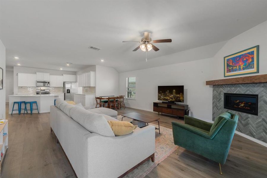 Living room featuring lofted ceiling, wood finished floors, visible vents, and baseboards