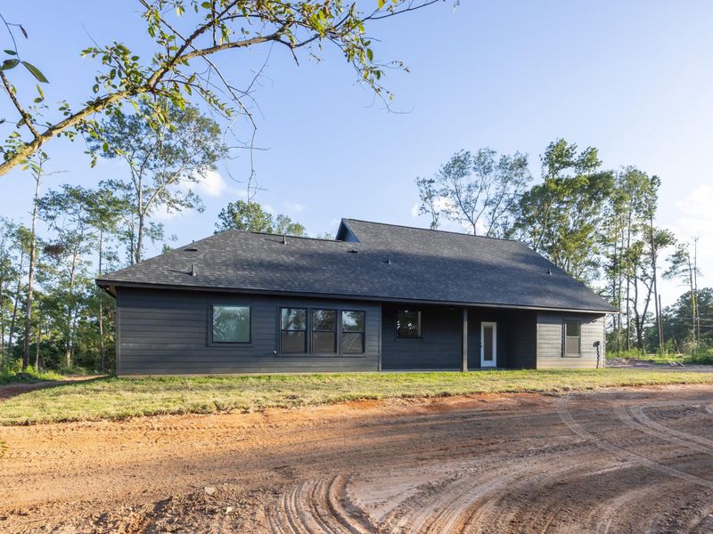 The clean lines and dark horizontal siding continue around the home’s rear exterior, where a covered back porch and large windows invite natural light indoors. The clean lines and dark horizontal siding continue around the home’s rear exterior, where a covered back porch and large windows invite natural light indoors.