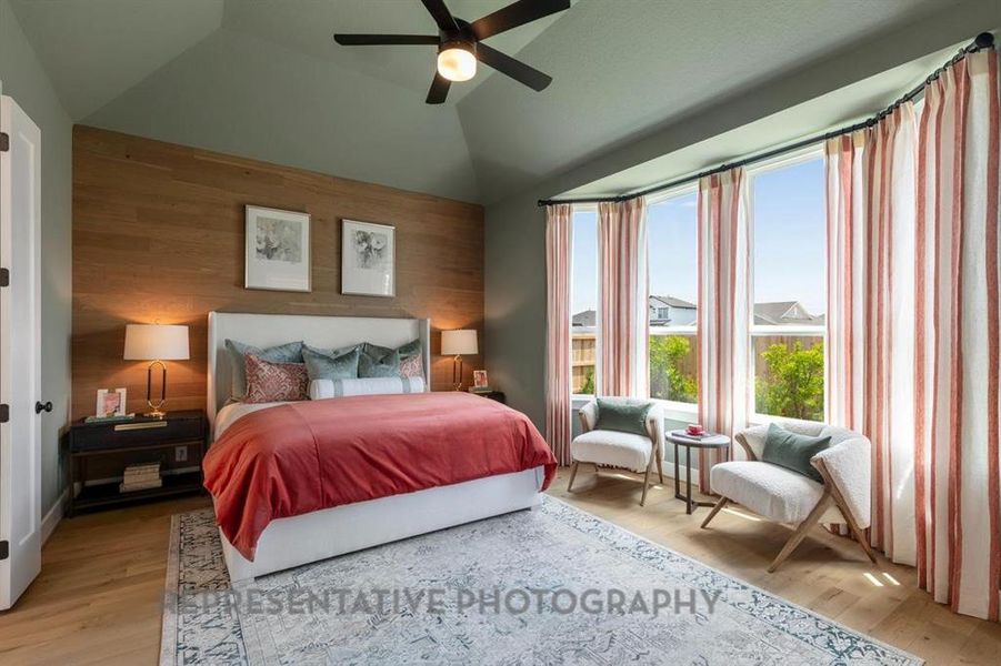 Bedroom with lofted ceiling, wooden walls, ceiling fan, and light wood-type flooring