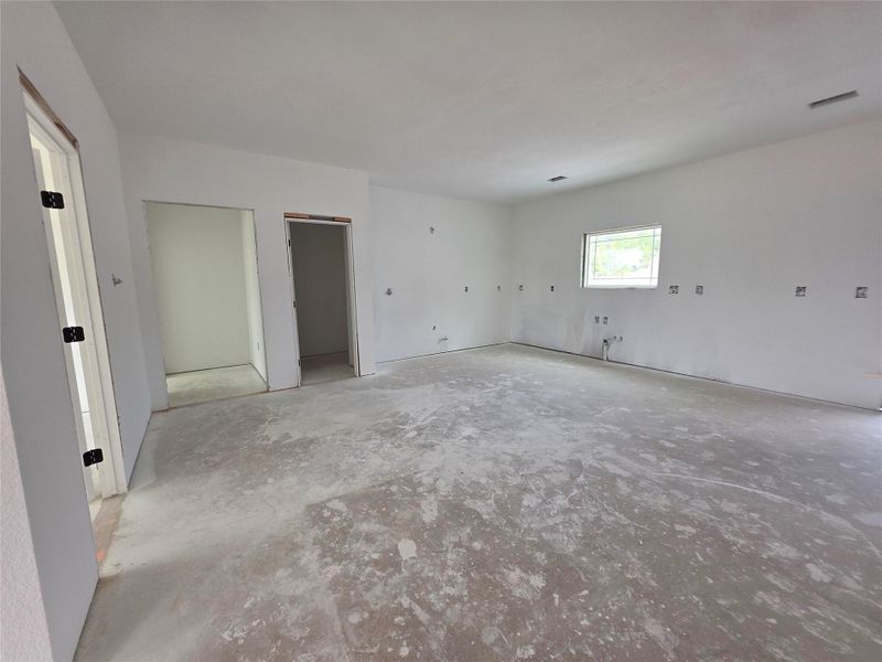 Spacious interior featuring a large window, multiple wall outlets, and an unfinished concrete floor