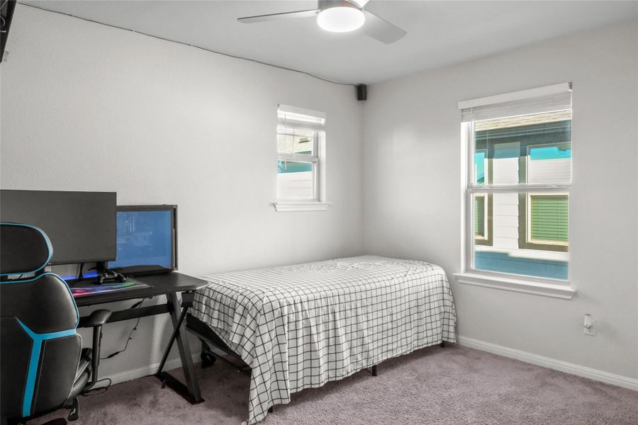 Carpeted bedroom with a ceiling fan and an office area