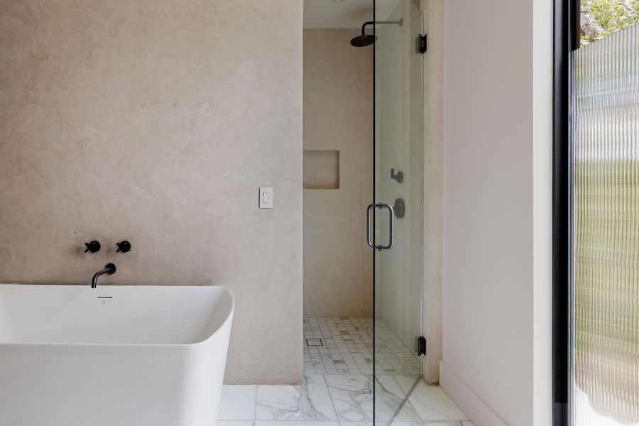 Bathroom with a shower stall, a freestanding bath, and marble finish flooring Bathroom with a shower stall, a freestanding bath, and marble finish flooring