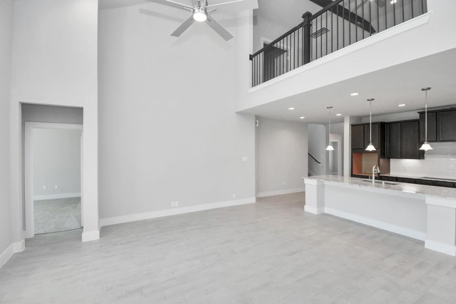 Gather the family and guests together in your lovely living room! Featuring soaring high ceilings, recessed lighting, ceiling fan, custom paint, gorgeous floors, and large windows that provide plenty of natural lighting throughout the day. Sample photo of completed home with similar floor plan. Actual colors and selections may vary.