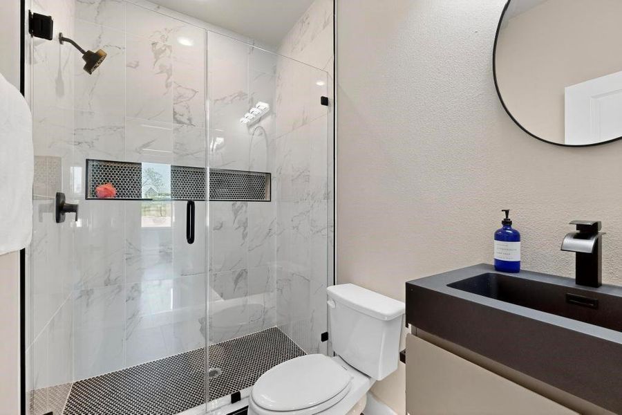 Full bath with a marble finish shower, vanity, and a textured wall