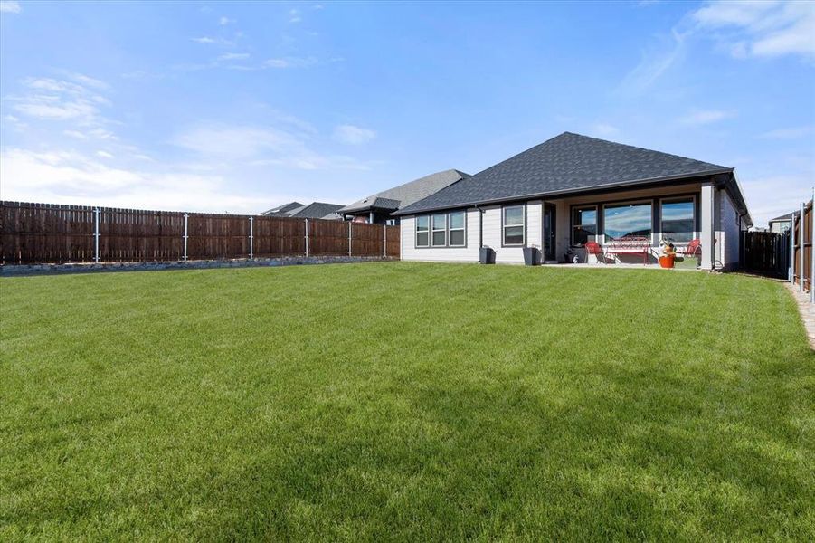 Rear view of property with a fenced backyard, a patio area, and a shingled roof Rear view of property with a fenced backyard, a patio area, and a shingled roof