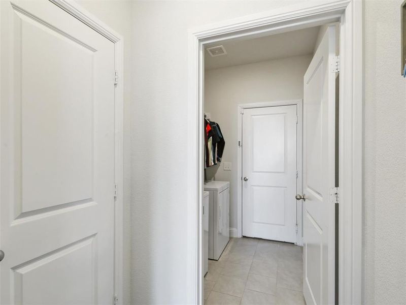 Clothes washing area with light tile patterned floors and washer and dryer