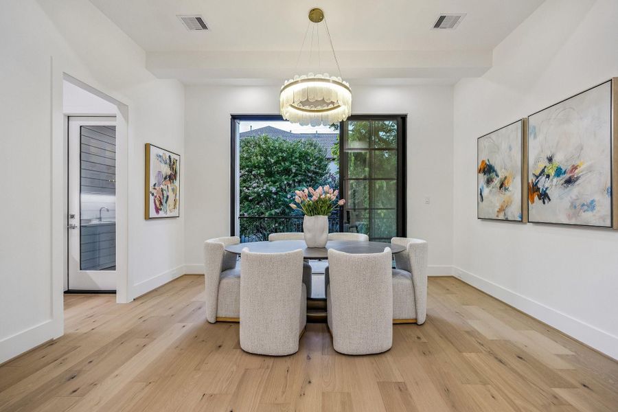 The dining room is a sophisticated blend of modern design and warm, livable comfort. The Painted Beamed Ceiling and the Modern Round 10-Light Tiered Clear Glass Chandelier becomes an artistic focal point, casting a gentle glow and adding movement and dimension to the room. Beyond the glass, a beautifully integrated wine room introduces both function and visual intrigue. Light wood flooring adds warmth underfoot. The Multi-Slide Panel Door offers effortless access to the Cigar Terrace. The dining room is a sophisticated blend of modern design and warm, livable comfort. The Painted Beamed Ceiling and the Modern Round 10-Light Tiered Clear Glass Chandelier becomes an artistic focal point, casting a gentle glow and adding movement and dimension to the room. Beyond the glass, a beautifully integrated wine room introduces both function and visual intrigue. Light wood flooring adds warmth underfoot. The Multi-Slide Panel Door offers effortless access to the Cigar Terrace.