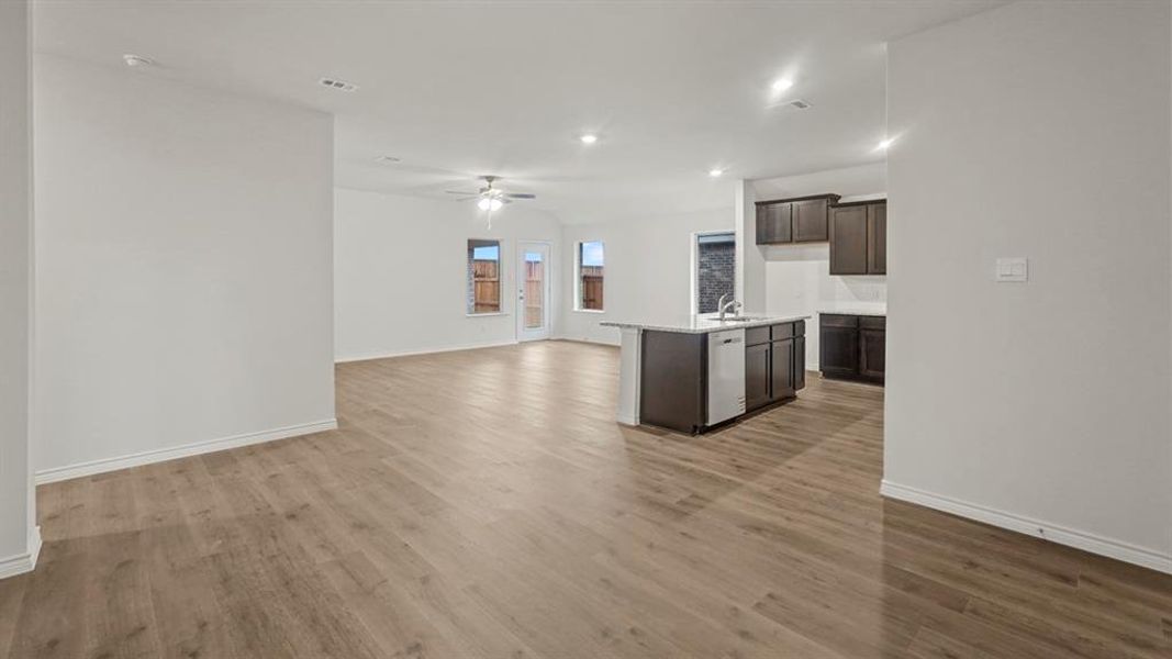 Kitchen with open floor plan, a kitchen island with sink, dark brown cabinets, dark wood-style flooring, and ceiling fan Kitchen with open floor plan, a kitchen island with sink, dark brown cabinets, dark wood-style flooring, and ceiling fan