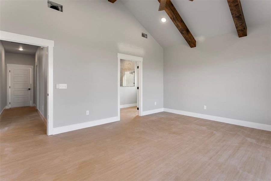 Empty room featuring beam ceiling, light hardwood / wood-style flooring, and high vaulted ceiling