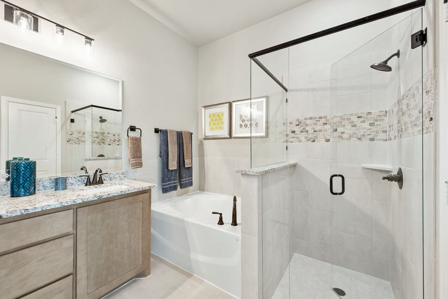 Bathroom with granite vanity, soaking tub, and glass-enclosed walk-in shower with tile accent strip Bathroom with granite vanity, soaking tub, and glass-enclosed walk-in shower with tile accent strip
