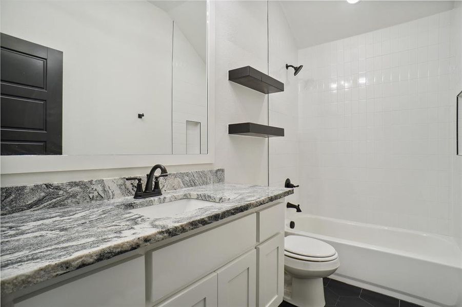 Full bathroom featuring vanity, tiled shower / bath combo, toilet, and tile patterned floors