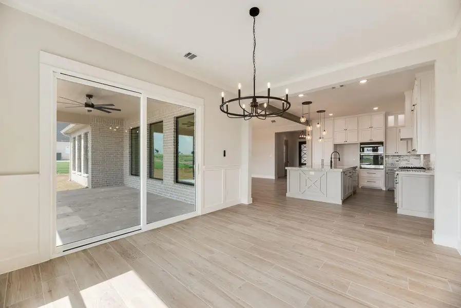 Kitchen featuring open floor plan, light countertops, ornamental molding, a chandelier, and white cabinetry Kitchen featuring open floor plan, light countertops, ornamental molding, a chandelier, and white cabinetry