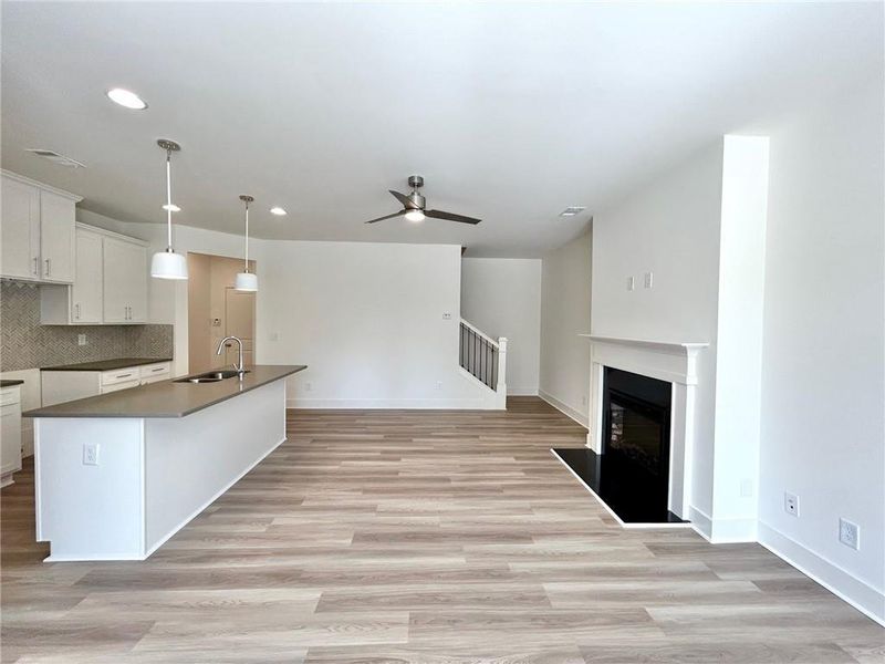 Kitchen featuring backsplash, ceiling fan, light hardwood / wood-style floors, and white cabinetry