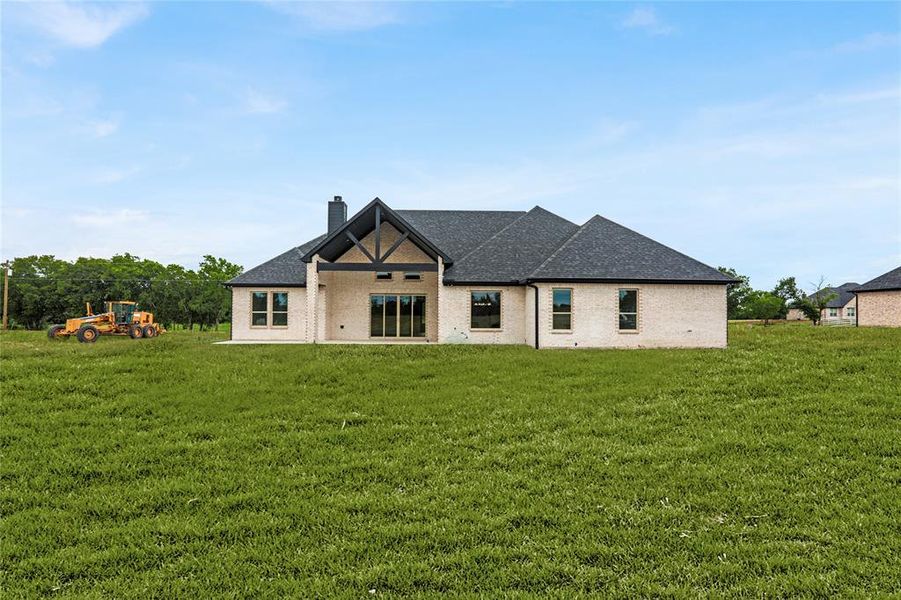 Back of house with a chimney, a lawn, roof with shingles, and brick siding Back of house with a chimney, a lawn, roof with shingles, and brick siding