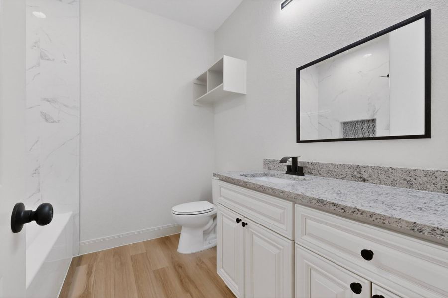 Modern bathroom featuring a white vanity with shaker-style cabinetry, a speckled countertop, and a rectangular undermount sink Modern bathroom featuring a white vanity with shaker-style cabinetry, a speckled countertop, and a rectangular undermount sink