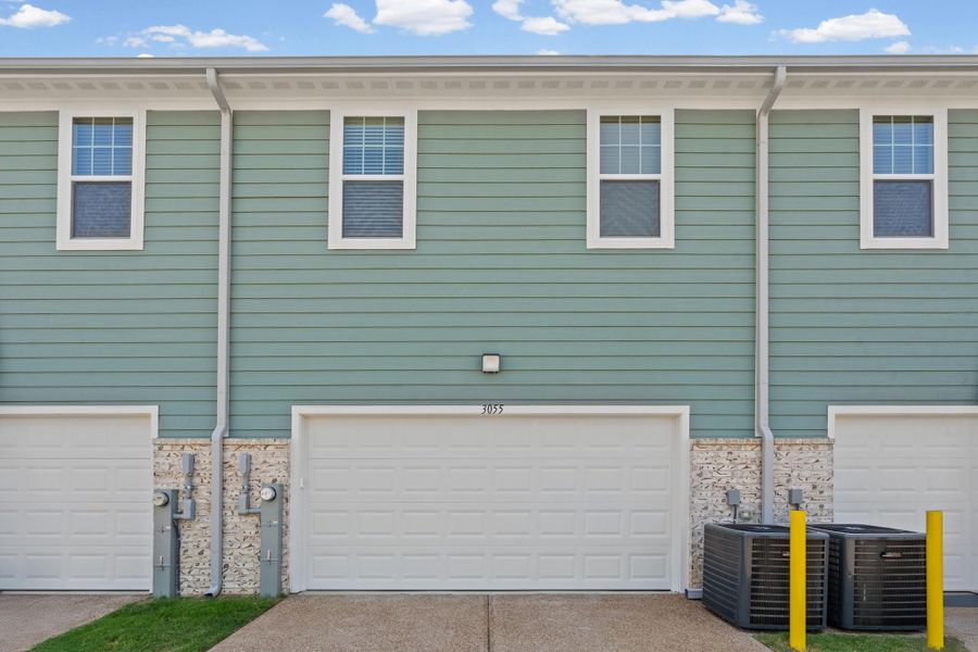 Hardie board siding with light stone accents, white frame windows, and an integrated garage