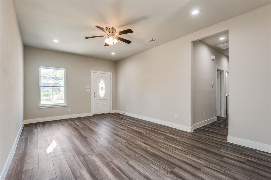 Foyer entrance into living room with dark wood style floors and a ceiling fan