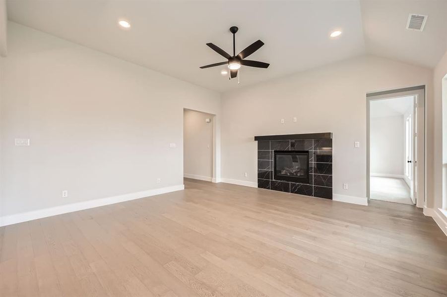 Unfurnished living room featuring vaulted ceiling, visible vents, light wood-type flooring, and a ceiling fan Unfurnished living room featuring vaulted ceiling, visible vents, light wood-type flooring, and a ceiling fan