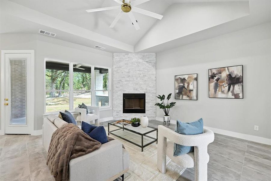 Living room with a fireplace, a ceiling fan, and high vaulted ceiling