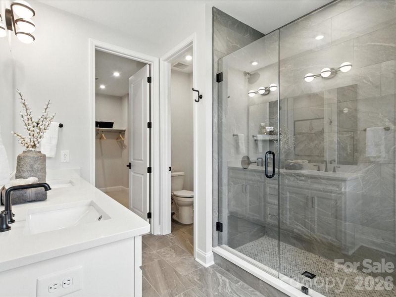 Dual vanity primary bathroom with tiled walk-in shower