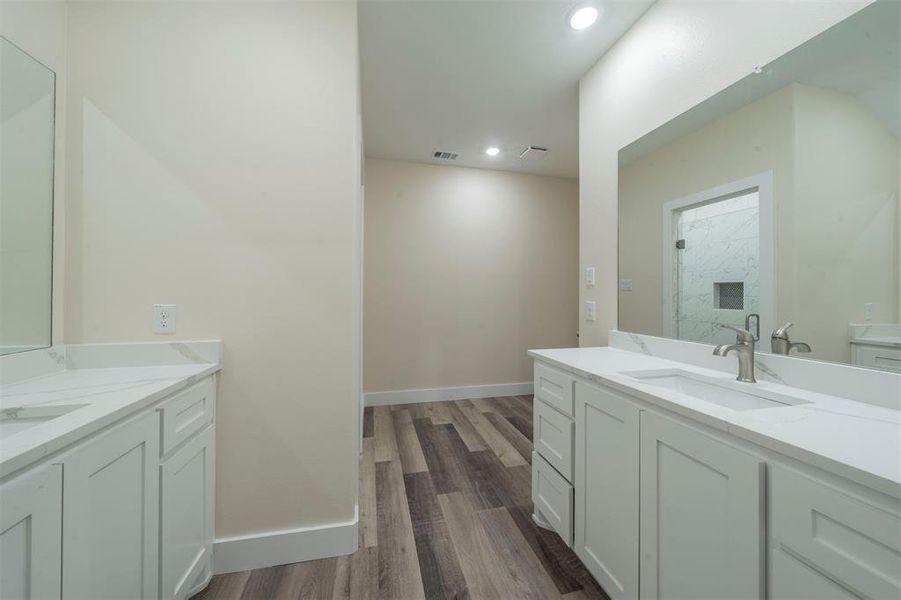 Bathroom with visible vents, wood finished floors, a sink, two vanities, and recessed lighting