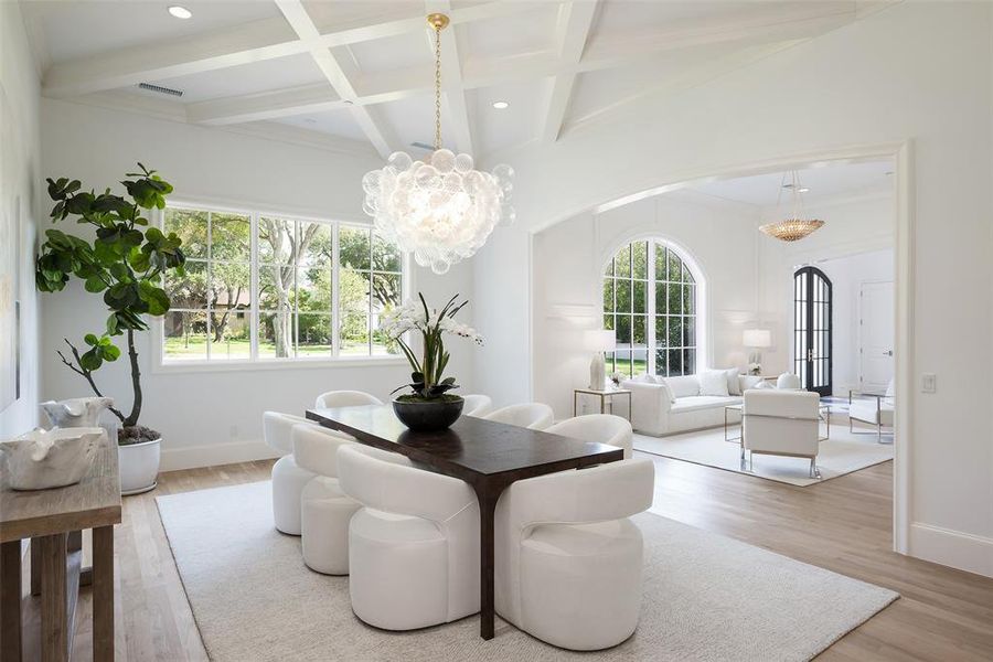 Dining room with a healthy amount of sunlight, light hardwood / wood floors, and coffered ceiling