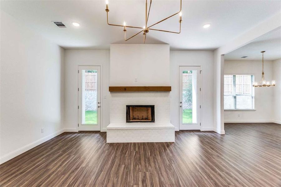 Unfurnished living room featuring a chandelier, a fireplace, dark wood-style floors, baseboards, and recessed lighting