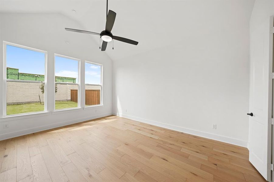 Unfurnished room with vaulted ceiling, light wood-style floors, and ceiling fan Unfurnished room with vaulted ceiling, light wood-style floors, and ceiling fan