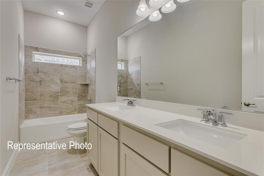 Full bathroom featuring vanity, toilet, tile patterned flooring, and tiled shower / bath