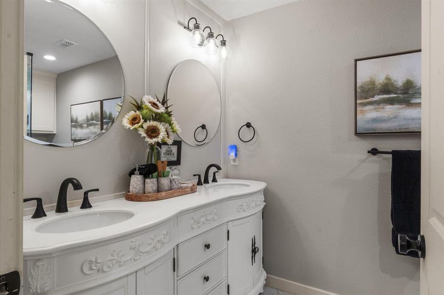 Primary bathroom with double vanity and baseboards Primary bathroom with double vanity and baseboards