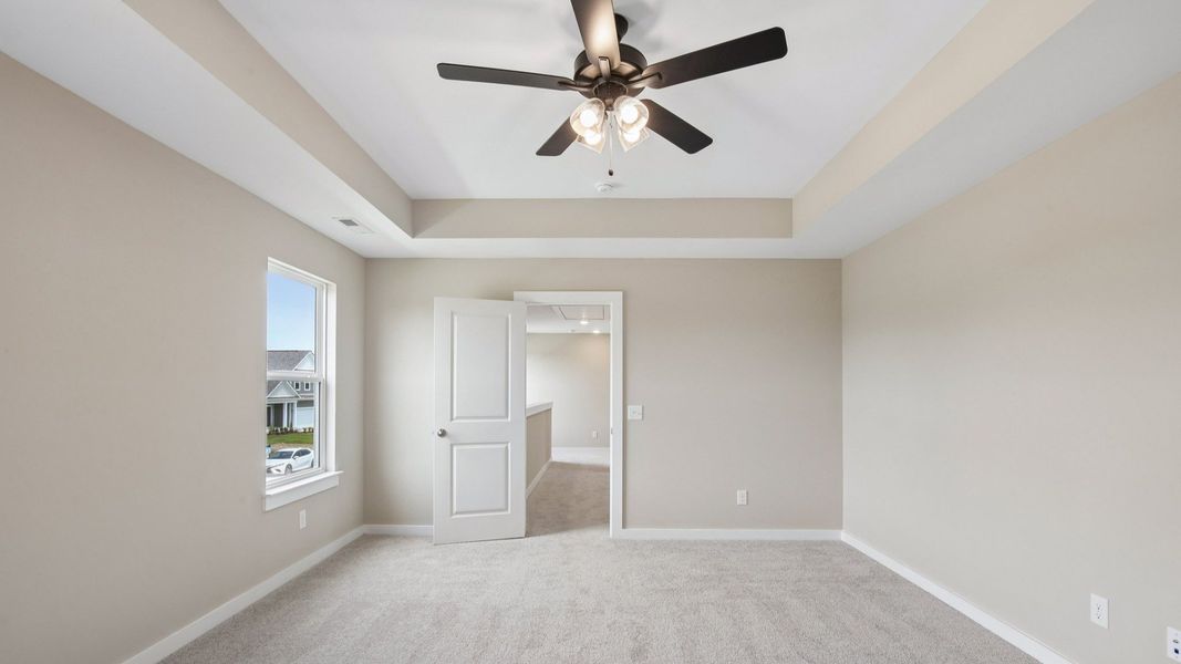 Bedroom with tray ceiling, windows, and entrance to primary bedroom Bedroom with tray ceiling, windows, and entrance to primary bedroom