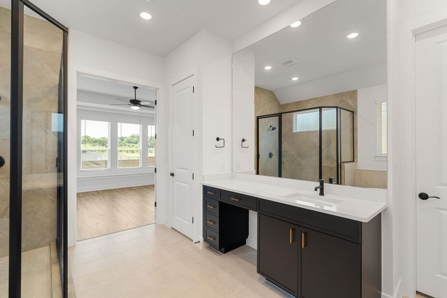 A primary bathroom showcases a spacious walk-in shower and a stylish vanity with ample counter space.