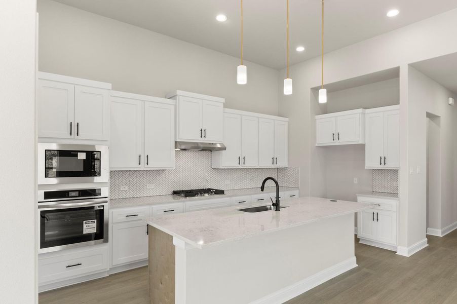 Kitchen with tasteful backsplash, hanging light fixtures, stainless steel appliances, white cabinetry, and recessed lighting Kitchen with tasteful backsplash, hanging light fixtures, stainless steel appliances, white cabinetry, and recessed lighting