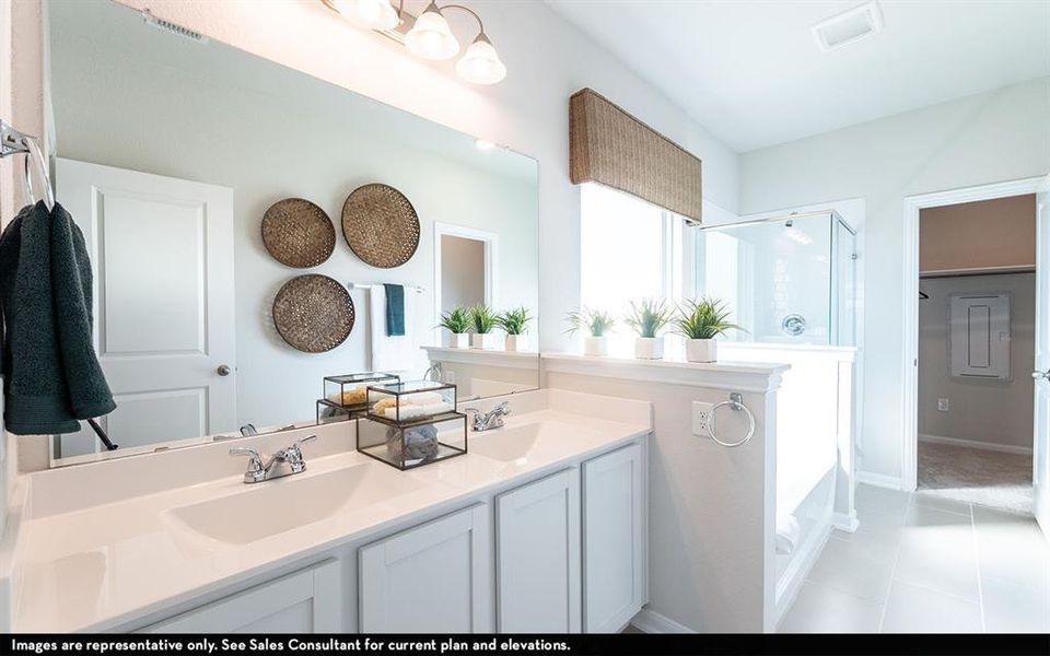 Bathroom featuring a dual vanity with white cabinetry and integrated sinks, a wide mirror, and a glass-enclosed shower