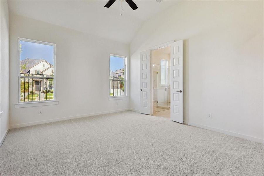 Unfurnished bedroom with ceiling fan, lofted ceiling, light carpet, and multiple windows