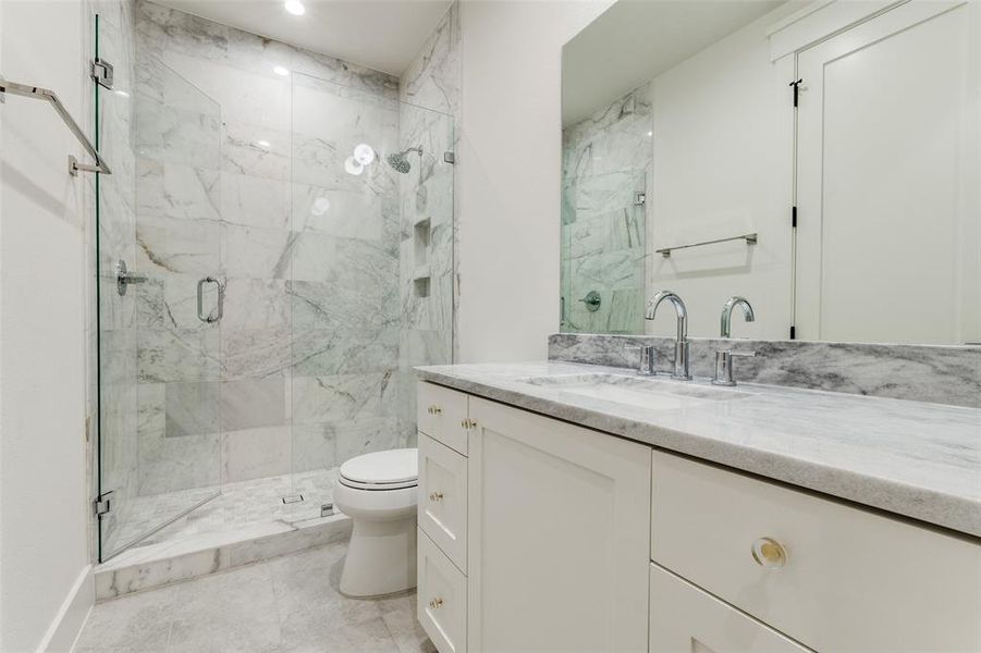 Bathroom featuring vanity, a shower with shower door, and toilet