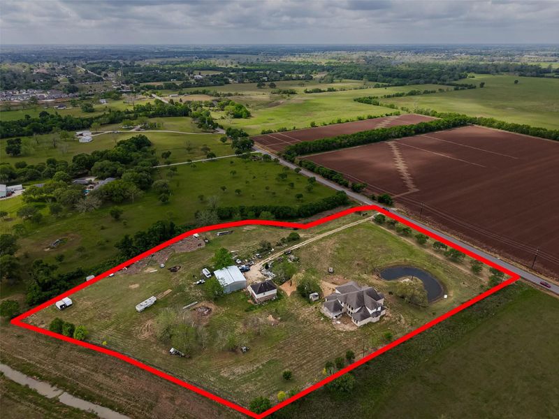 Aerial view of the property with outlined boundaries, multiple improvements, pond, and surrounding rural landscape.