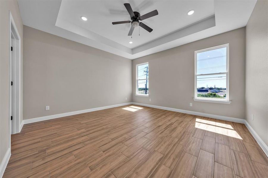 Spare room with a tray ceiling, light wood-type flooring, a ceiling fan, and recessed lighting Spare room with a tray ceiling, light wood-type flooring, a ceiling fan, and recessed lighting