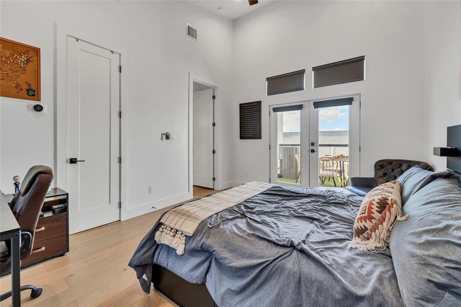 Bedroom with light wood finished floors, a towering ceiling, a desk, and access to outside Bedroom with light wood finished floors, a towering ceiling, a desk, and access to outside