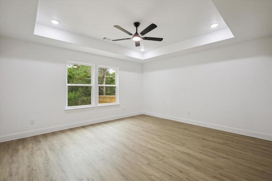 Unfurnished room with a tray ceiling, light wood-style floors, recessed lighting, and a ceiling fan Unfurnished room with a tray ceiling, light wood-style floors, recessed lighting, and a ceiling fan