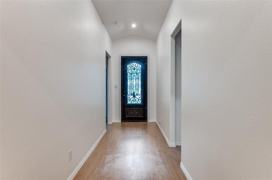 Doorway featuring vaulted ceiling and light hardwood / wood-style floors