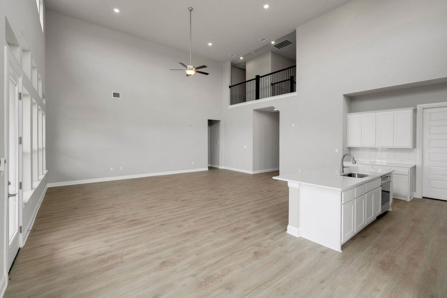 Kitchen with ceiling fan, open floor plan, light countertops, light wood-style flooring, and a towering ceiling Kitchen with ceiling fan, open floor plan, light countertops, light wood-style flooring, and a towering ceiling
