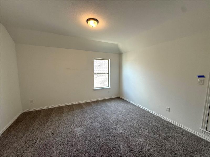 Unfurnished room with dark colored carpet and lofted ceiling Unfurnished room with dark colored carpet and lofted ceiling