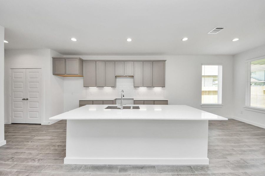 The kitchen is a culinary haven, featuring granite countertops, a tile backsplash, stainless steel appliances, 42” upper cabinets, and undercabinet lighting. Sample photo of completed home with similar floor plan. Actual colors and selections may vary. The kitchen is a culinary haven, featuring granite countertops, a tile backsplash, stainless steel appliances, 42” upper cabinets, and undercabinet lighting. Sample photo of completed home with similar floor plan. Actual colors and selections may vary.