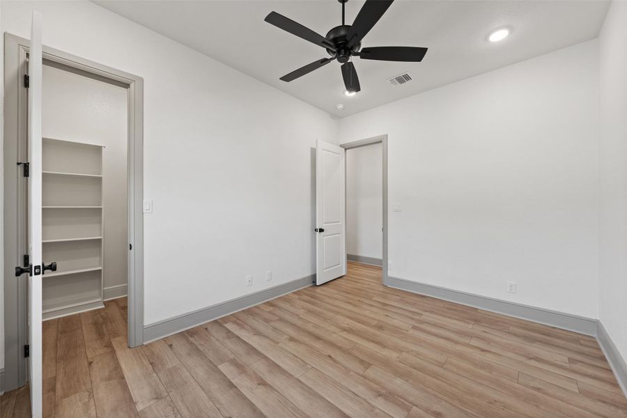 Unfurnished bedroom with visible vents, a walk in closet, baseboards, recessed lighting, and light wood-style flooring
